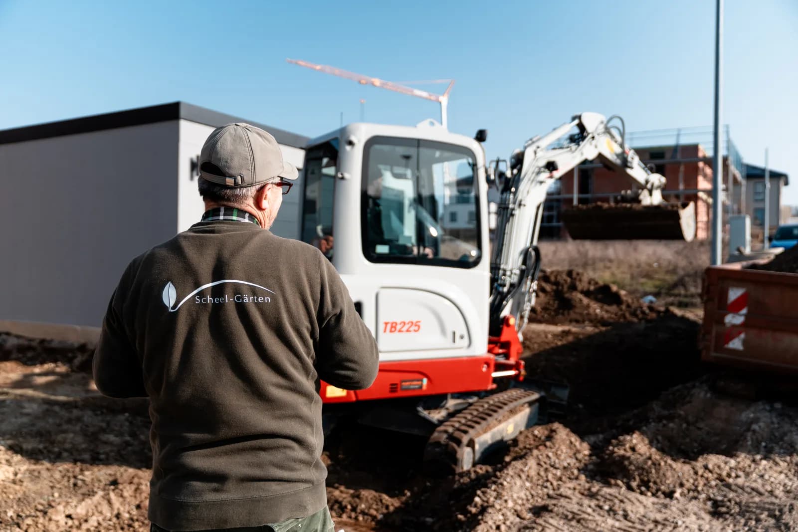 Scheel-Mitarbeiter am Minibagger auf einer Baustelle